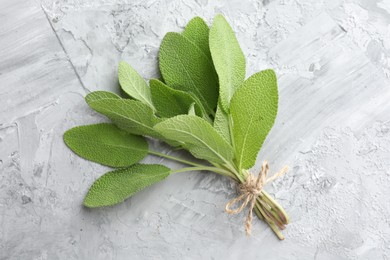 Photo of Bunch of fresh sage leaves on gray textured table, top view