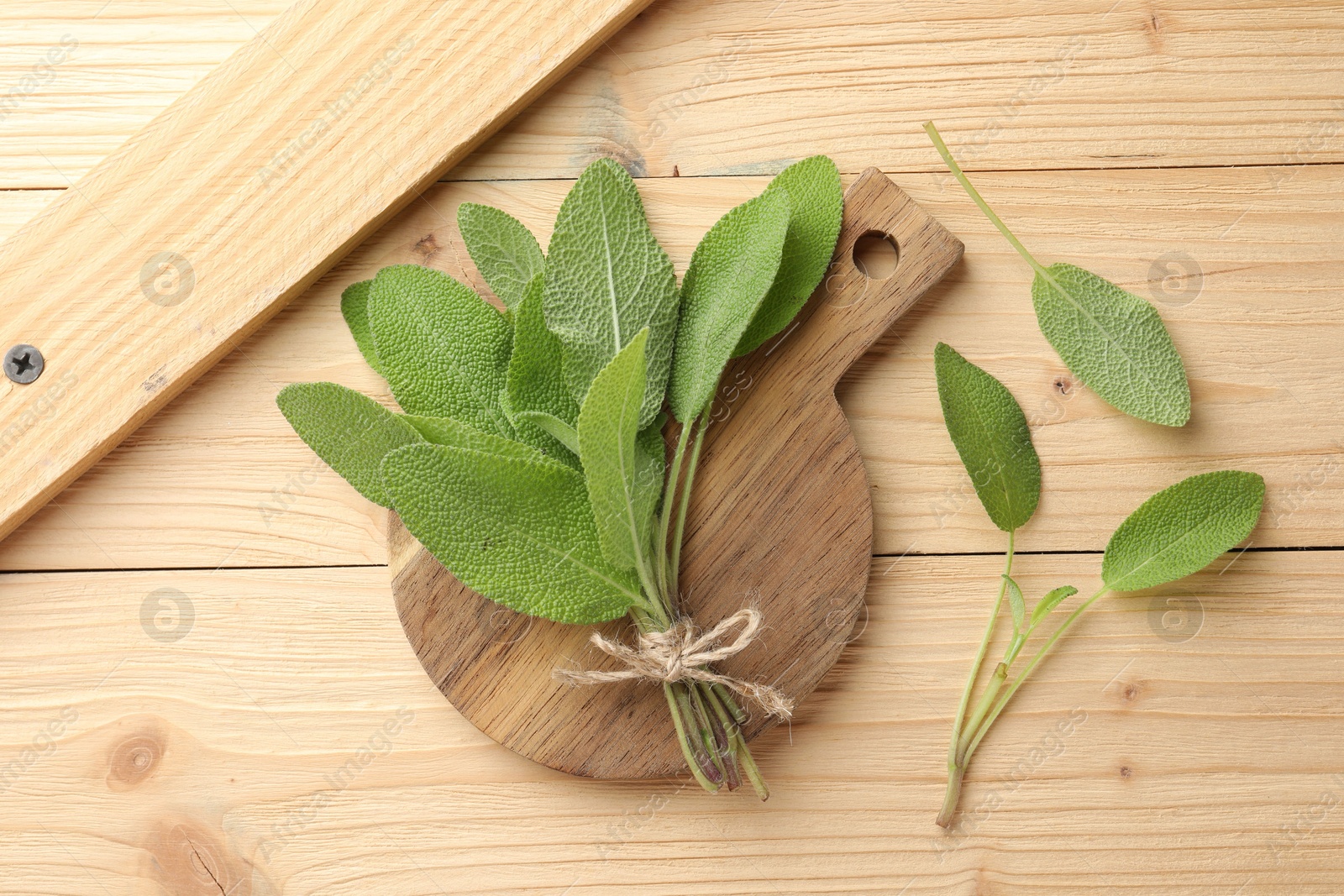 Photo of Bunch of fresh sage leaves on wooden table, flat lay