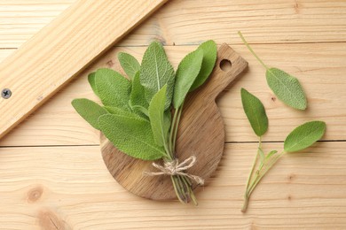 Photo of Bunch of fresh sage leaves on wooden table, flat lay