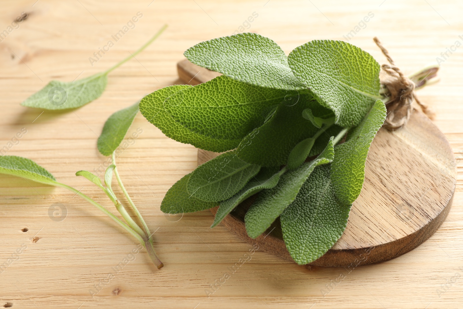 Photo of Bunch of fresh sage leaves on wooden table, closeup