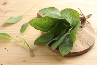 Photo of Bunch of fresh sage leaves on wooden table, closeup