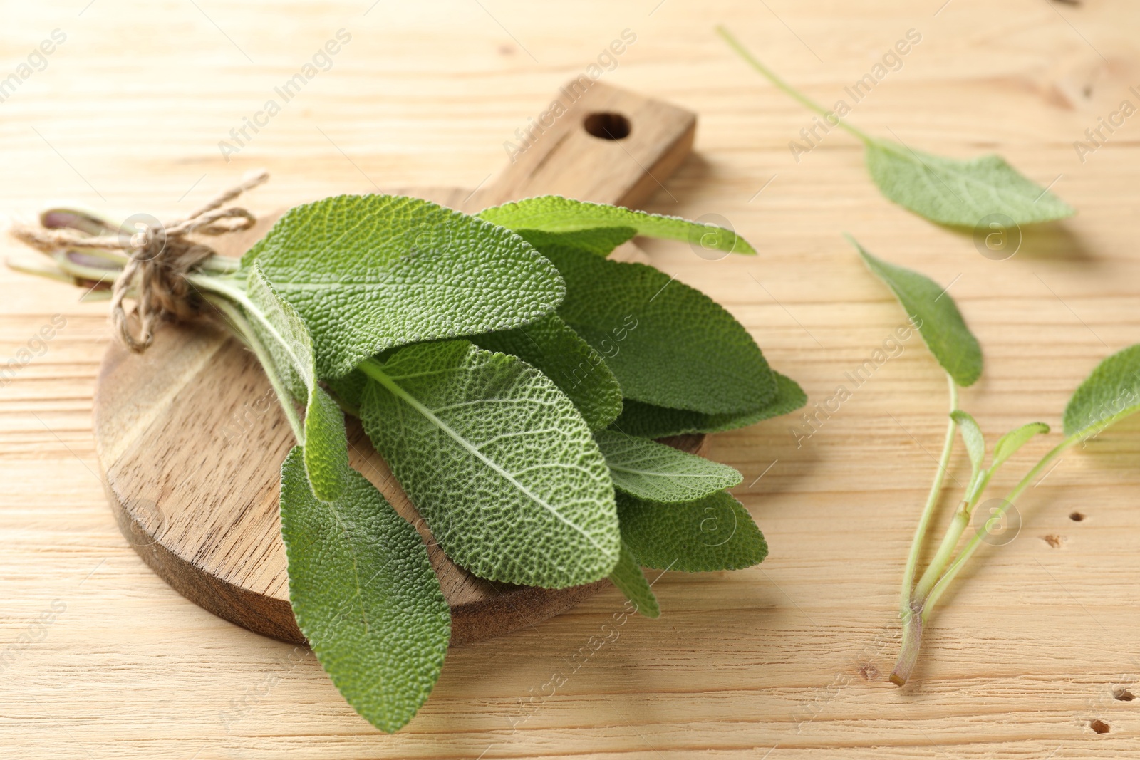 Photo of Bunch of fresh sage leaves on wooden table, closeup