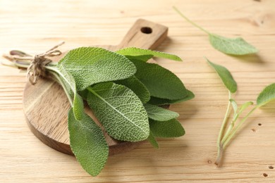 Photo of Bunch of fresh sage leaves on wooden table, closeup