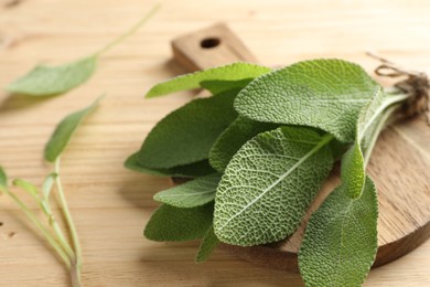 Photo of Bunch of fresh sage leaves on wooden table, closeup