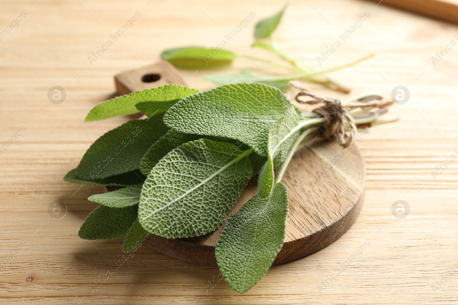 Photo of Bunch of fresh sage leaves on wooden table, closeup