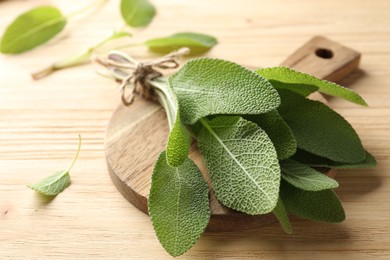 Photo of Bunch of fresh sage leaves on wooden table, closeup