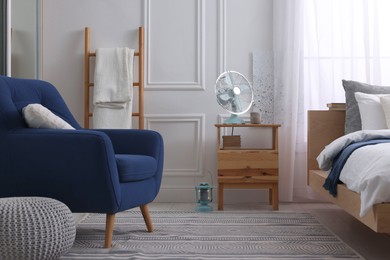 Stylish living room interior with bed, bedside table and fan