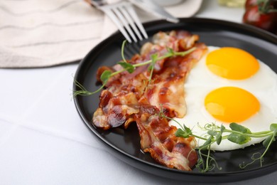 Fried eggs and bacon served on white table, closeup