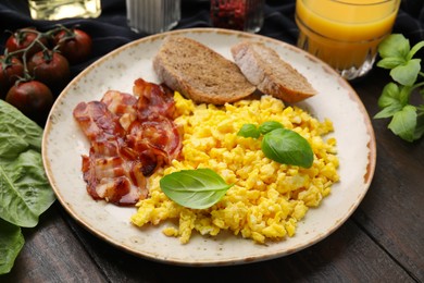 Photo of Delicious scrambled eggs with bacon and products on wooden table