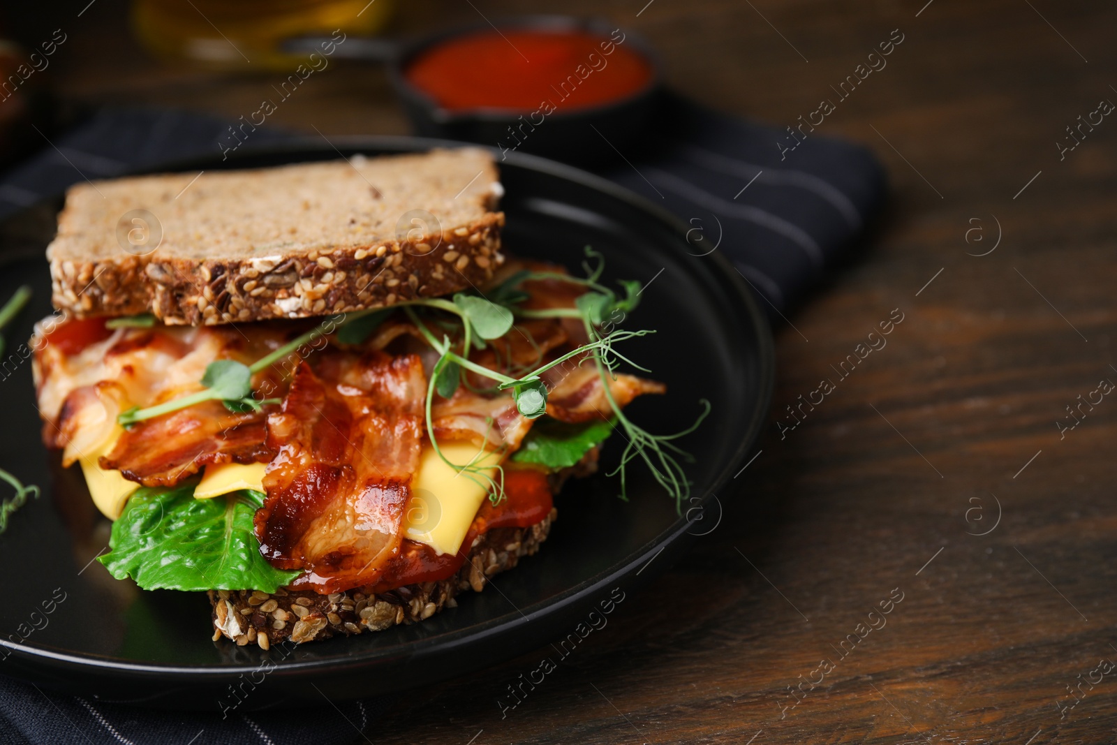 Photo of Tasty sandwich with bacon and cheese on wooden table, closeup. Space for text