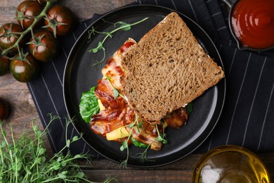 Photo of Tasty sandwich with bacon and microgreens served on wooden table, flat lay