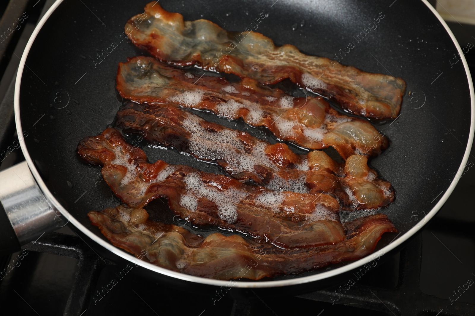 Photo of Slices of bacon frying in pan, closeup