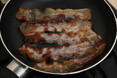 Slices of bacon frying in pan, closeup