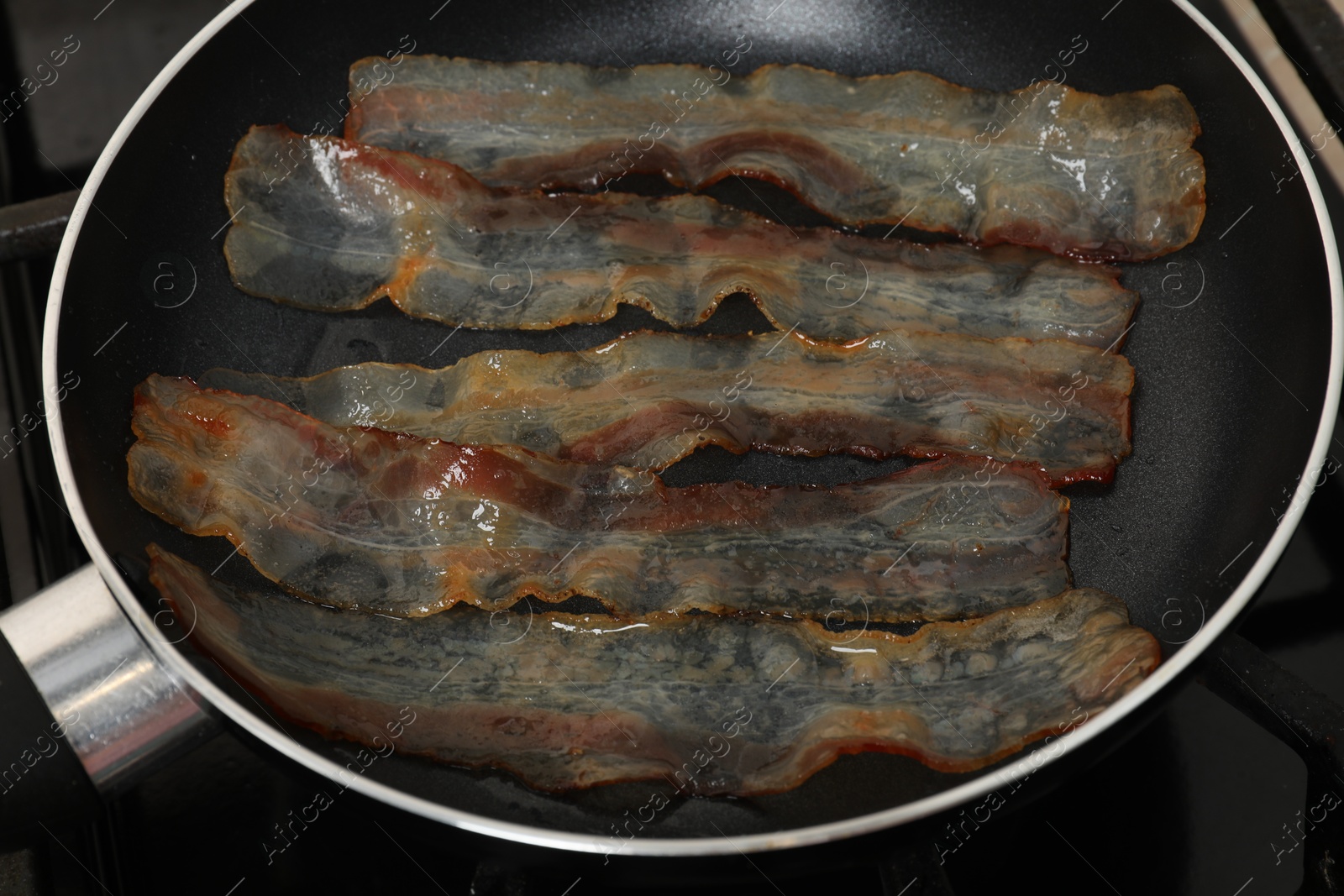 Photo of Slices of bacon frying in pan, closeup