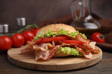 Photo of Delicious burger with bacon, tomato and lettuce on wooden table