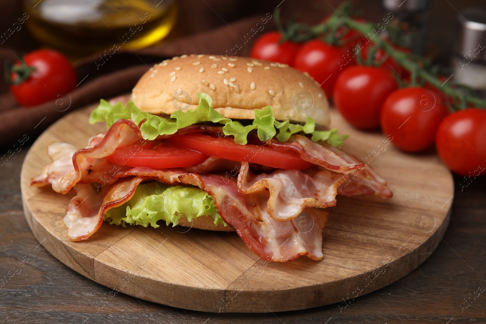 Photo of Delicious burger with bacon, tomato and lettuce on wooden table