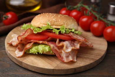 Delicious burger with bacon, tomato and lettuce on wooden table