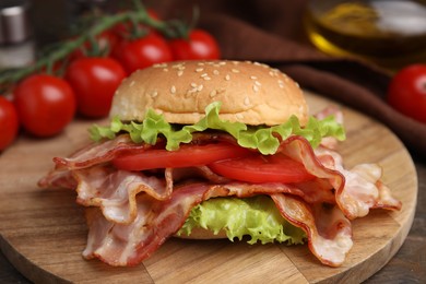 Photo of Delicious burger with bacon, tomato and lettuce on table