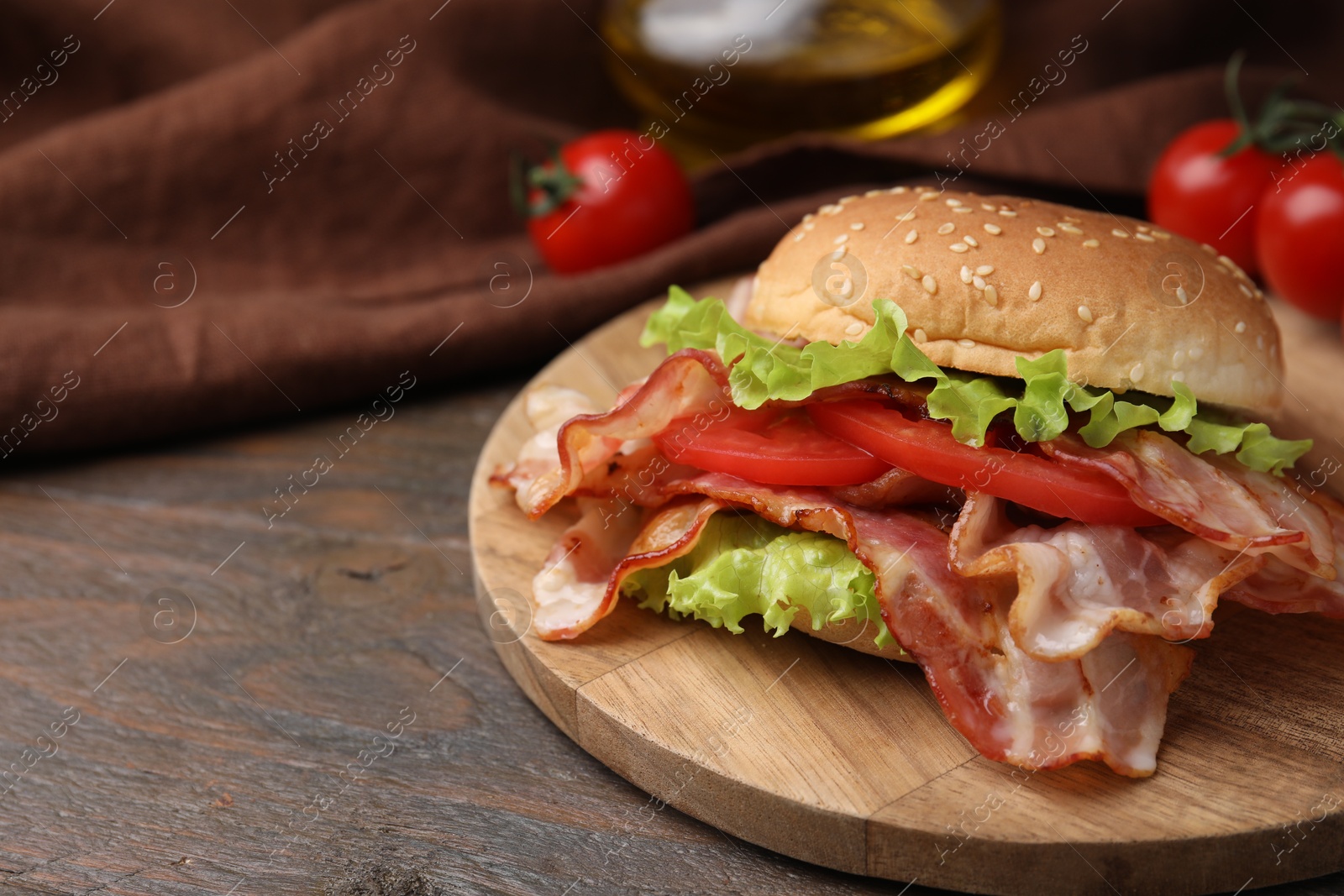 Photo of Delicious burger with bacon, tomato and lettuce on wooden table. Space for text