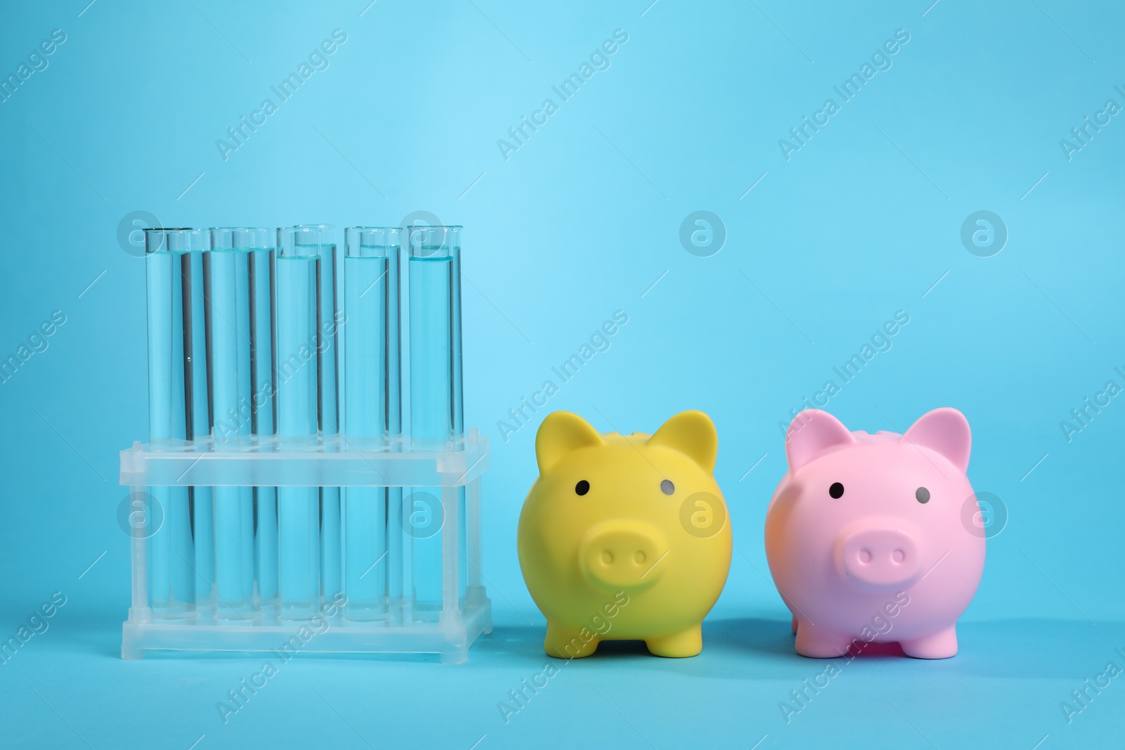 Water save concept. Piggy banks and liquid in test tubes on light blue background Photo of Water save concept. Piggy banks and liquid in test tubes on light blue background