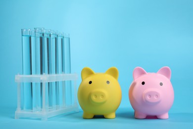 Photo of Water save concept. Piggy banks and liquid in test tubes on light blue background