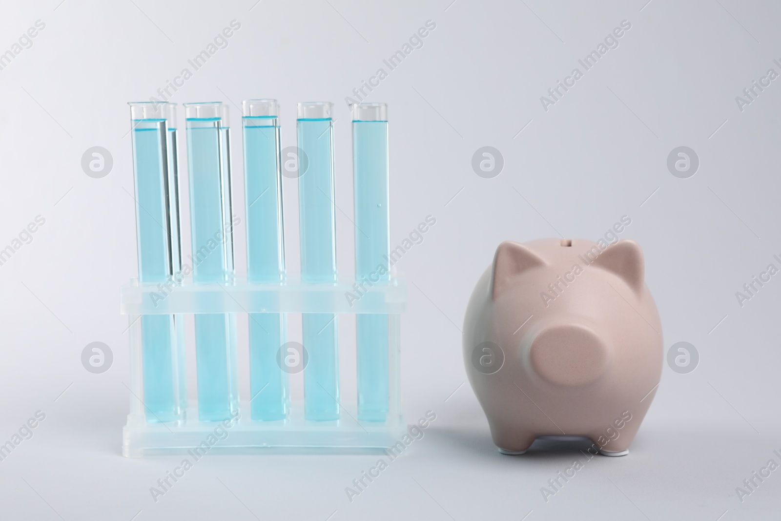 Water save concept. Piggy bank and liquid in test tubes on light grey background Photo of Water save concept. Piggy bank and liquid in test tubes on light grey background