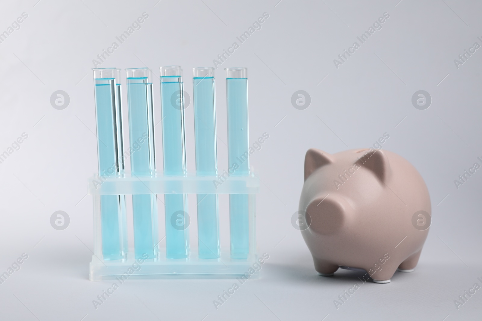 Photo of Water save concept. Piggy bank and liquid in test tubes on light grey background