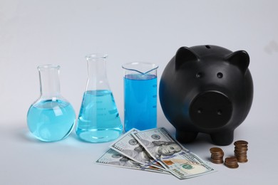 Photo of Water save concept. Piggy bank, money and laboratory glassware with liquid on light grey background