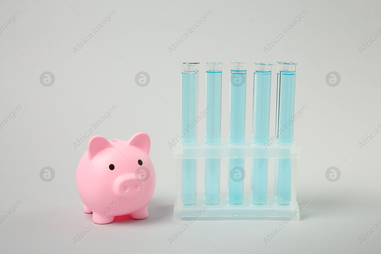 Photo of Water save concept. Piggy bank and liquid in test tubes on light grey background