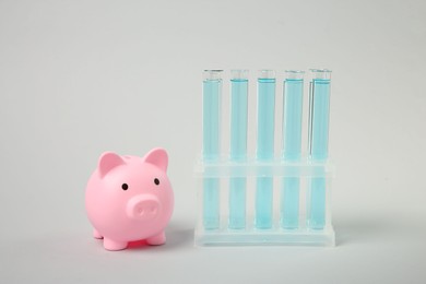 Water save concept. Piggy bank and liquid in test tubes on light grey background