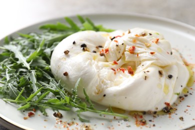 Photo of Delicious burrata cheese, arugula and spices on plate, closeup