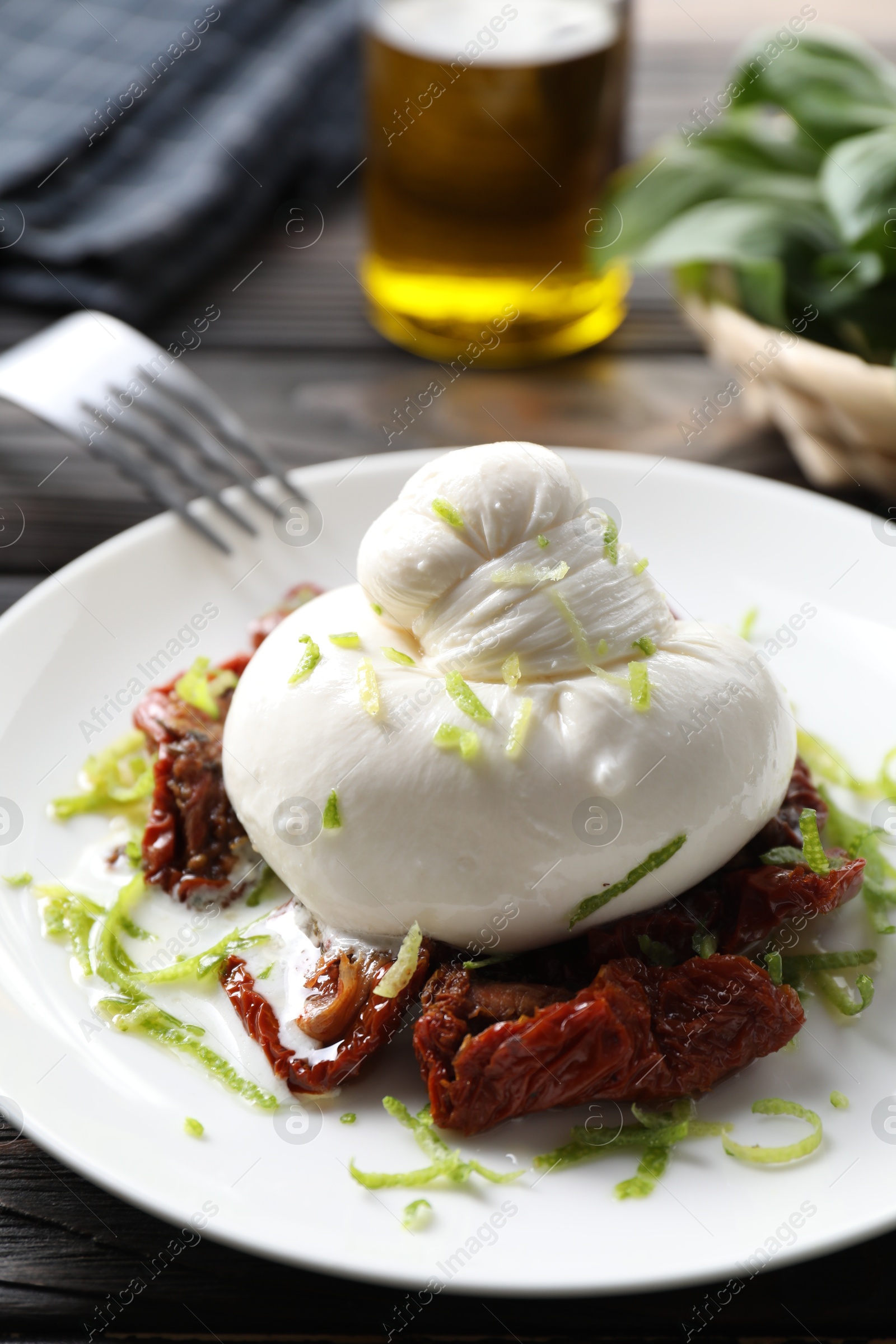 Photo of Delicious burrata cheese and sun-dried tomatoes on wooden table, closeup