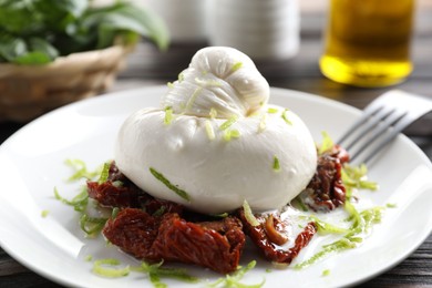 Photo of Delicious burrata cheese and sun-dried tomatoes on table, closeup