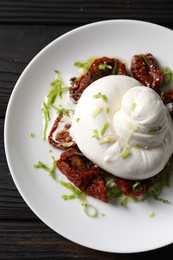 Delicious burrata cheese and sun-dried tomatoes on wooden table, top view