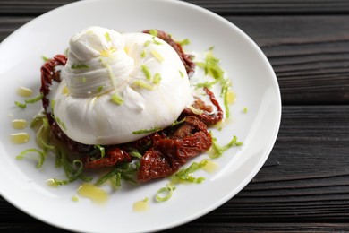 Photo of Delicious burrata cheese and sun-dried tomatoes on wooden table, closeup