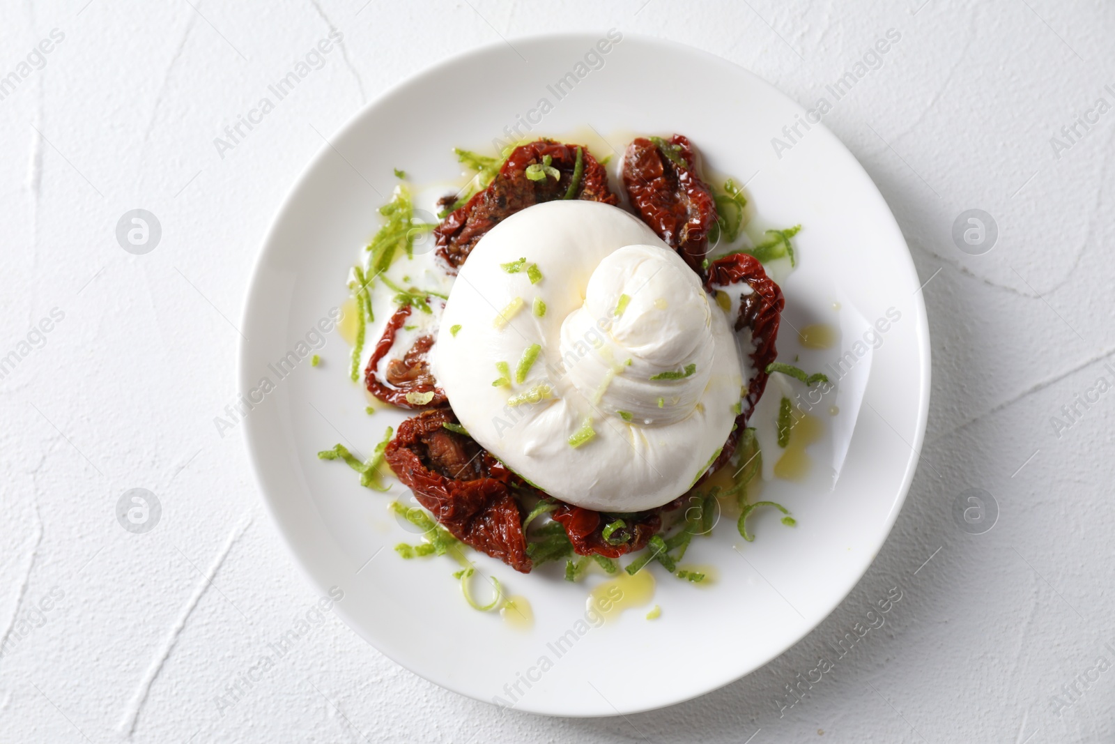 Photo of Delicious burrata cheese and sun-dried tomatoes on white table, top view