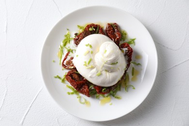 Delicious burrata cheese and sun-dried tomatoes on white table, top view