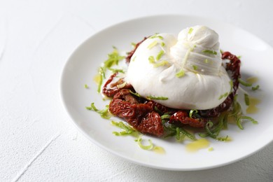 Photo of Delicious burrata cheese and sun-dried tomatoes on white table, closeup