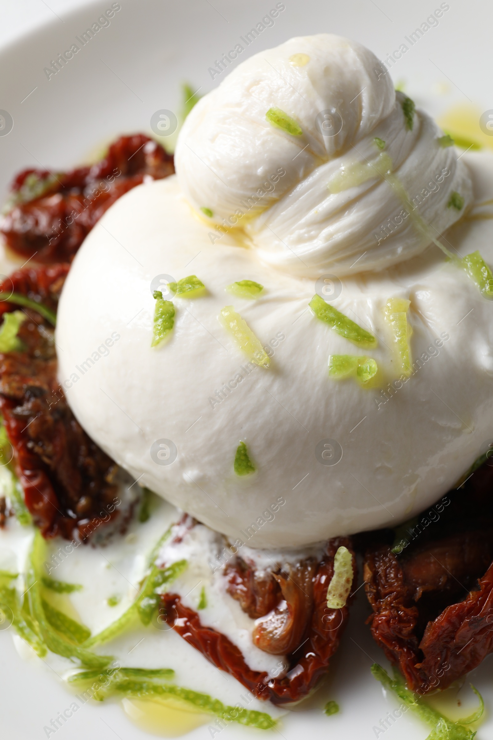 Photo of Delicious burrata cheese and sun-dried tomatoes on plate, closeup