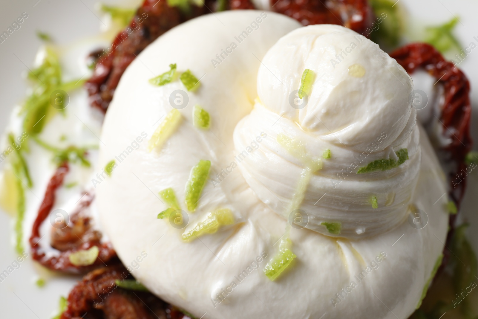 Photo of Delicious burrata cheese and sun-dried tomatoes on plate, closeup