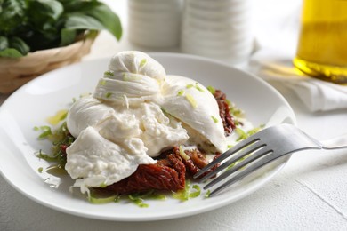 Photo of Delicious burrata cheese and sun-dried tomatoes served on white table, closeup