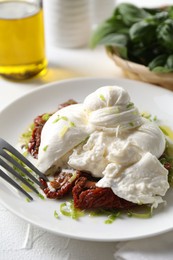 Photo of Delicious burrata cheese and sun-dried tomatoes served on white table, closeup