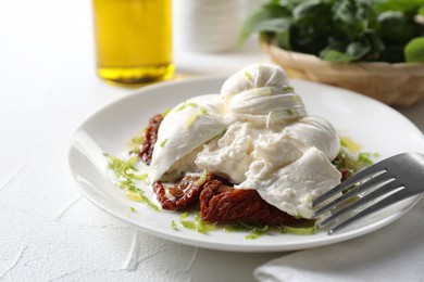 Photo of Delicious burrata cheese and sun-dried tomatoes served on white table, closeup