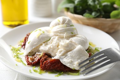 Delicious burrata cheese and sun-dried tomatoes served on white table, closeup