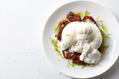 Delicious burrata cheese and sun-dried tomatoes on white table, top view. Space for text