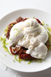 Photo of Delicious burrata cheese and sun-dried tomatoes on white table, closeup