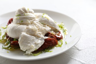 Delicious burrata cheese and sun-dried tomatoes on white table, closeup