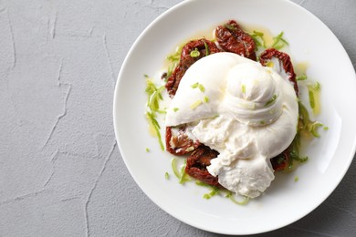 Delicious burrata cheese and sun-dried tomatoes on light grey table, top view. Space for text