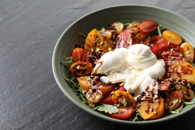 Photo of Fresh delicious burrata salad on black table, closeup