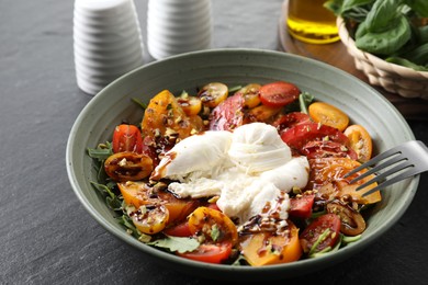 Fresh delicious burrata salad served on black table, closeup